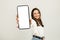 Smiling young brunette woman in a white blouse presenting a smartphone with a blank screen