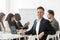 Smiling young businessman in suit looking at camera at meeting