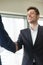 Smiling young businessman wearing black suit shaking male hand,