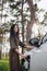 Smiling young caucasian woman plugging electricity cable in electric vehicle for charging on sunny mall parking, cropped