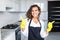 Smiling young cleaning lady with pink rubber gloves showing ok sign with thumbs up in the kitchen