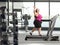 Smiling young corpulent woman walking on a treadmill at the gym and waving