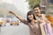 Smiling young couple with colorful shopping bags hailing a taxicab on the street in Beijing, China