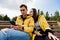 Smiling young couple in yellow jackets sitting on a bench in the autumn Park using phones, smartphones. Millennials, inseparable