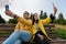 Smiling young couple in yellow jackets take a selfie, photo on a smartphone, phone, sitting on a bench in the autumn Park.