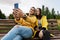 Smiling young couple in yellow jackets take a selfie, photo on a smartphone, phone, sitting on a bench in the autumn Park.