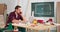 Smiling young craftsman sitting at a workbench in his carpentry workshop working online with a laptop and discussing