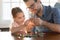 Smiling young daddy helping small preschool daughter making bracelets.