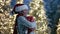 Smiling young dark-skinned woman in Christmas hat hugging a gift box outdoors