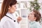 Smiling young doctor examining throat to child patient