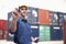 Smiling young engineer in protective work wear in a shipping yard examining cargo