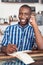 Smiling young entrepreneur talking on a cellphone in his cafe