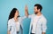 Smiling young european man and arab lady make high five hands sign, celebrating victory and success, have fun