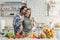 Smiling young european woman prepares salad, man with stubble hugs wife at table with organic vegetables