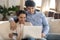 Smiling young family couple shopping at internet store using laptop