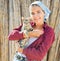 Smiling young female farmer holding tabby kitten in hands