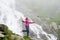 Smiling young female making selfie posing on rock in front of magnificent Balea waterfall in Romania