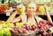 Smiling young female seller holding bunch of grapes on market