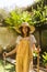 Smiling young gardener with straw hat with rake and shovel in her hands. Gardening.