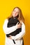 Smiling young girl dressed white hoodie on yellow background with backpack. Positive cool schoolgirl