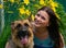Smiling young girl with faithful friend on the background of flowers