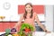 smiling young girl in a kitchen, standing behind a pile vegetables.