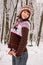 Smiling young girl in knitted cozy wear posing in snowy winter forest. Winter weather and clothes concept. Happy woman in winter p