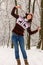 Smiling young girl in knitted cozy wear posing in snowy winter forest. Winter weather and clothes concept. Happy woman in winter p