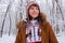 Smiling young girl in knitted cozy wear in snowy winter forest. Winter weather and clothes concept. Christmas background.