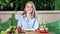 Smiling young girl posing at kitchen table surrounded by fresh healthy vegetables looking at camera