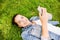 Smiling young girl with smartphone lying on grass