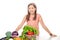 Smiling young girl standing behind a pile vegetables