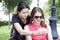 Smiling young girls with cell phone sitting on a bench in a park