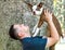 Smiling young Hispanic man holding puppy up in the air