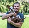 Smiling young Hispanic man hugging a puppy