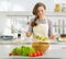 Smiling young housewife mixing fresh salad