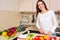 Smiling young housewife mixing fresh salad