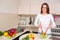 Smiling young housewife mixing fresh salad