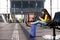 Smiling young Indian woman sitting at station with bags and looking at cellphone