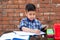 Smiling young male kid using digital smartphone watching online e-learning video to studying in classroom , Asian Indian schoolboy