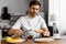 Smiling young man applying jam onto toast on weekend morning