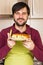 Smiling young man with apron holding a plate with homemade cake