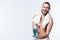 Smiling young man with bath towel around his neck holding bottle with tooth rinse in hands,
