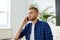 Smiling young man calling on smartphone at office