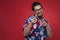 Smiling young man in Hawaiian shirt pointing towards camera