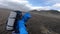 Smiling Young man hikes through rough Iceland terrain during strong wind up to 30 miters per second on the Fimmvorduhals