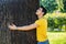 Smiling young man hugging a tree, looking up