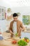 Smiling young man making vegetables salad in the kitchen at home