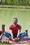 Smiling young man practice yoga summer day by the lake pose for stretching the hips