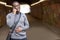 Smiling Young Man In Urban Setting Standing In Tunnel Talking On Mobile Phone